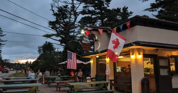 Multiple countries flags hang off the front of the ice cream parlor over picnic tables.