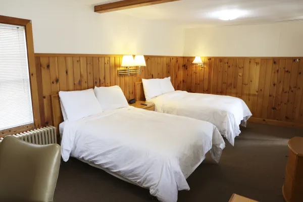 Plush white linens on two queen beds at The Ashley.