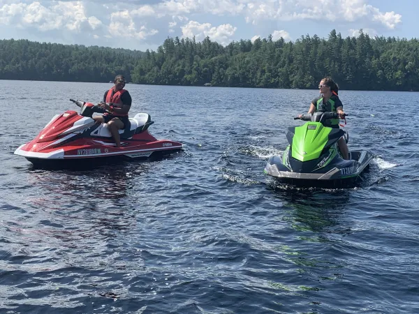 A couple of jet skiers sit on the water.