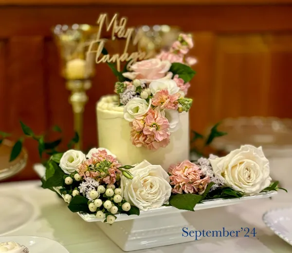 A single tier cake decorated with white and pink flowers.