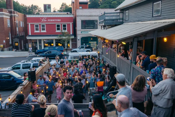 A crowd of people dance at an outdoor music venue in the middle of a small town. 