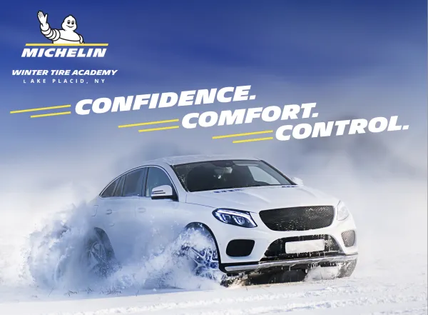 White sedan drives in snow with Michelin logo and the words Confidence, comfort, and control above it against blue sky