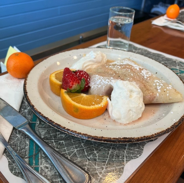 A crepe and fresh fruit on a plate.