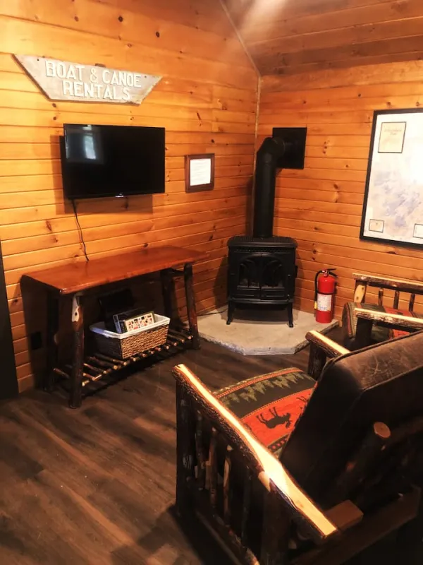 The living space with two rustic arm chairs, wood stove and tv at Rockledge Cabins & Retreats 