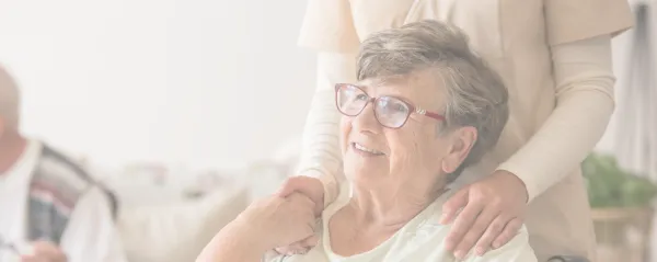 An older woman with red glasses smiles to something off camera
