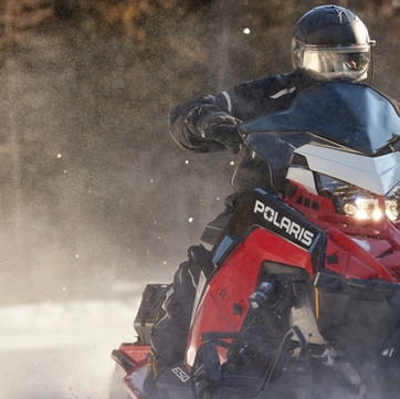 A person riding a red and black snow machine through the snow