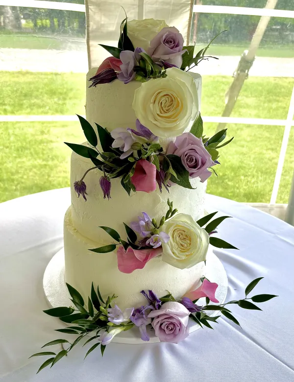 A three tiered cake decorated with pastel colored roses.