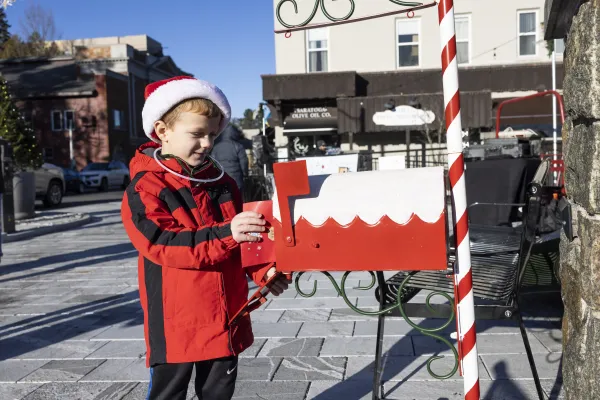 Image of a child putting his letter to Santa into a mailbox.
