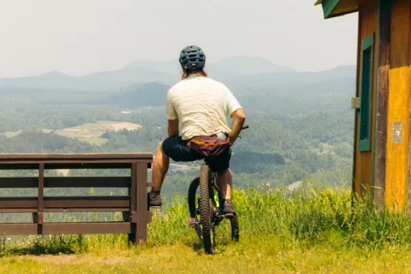 A mountain biker enjoys mountain views up a summit bench