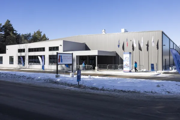 A snowy exterior of the Saranac Lake Civic Center and sign.