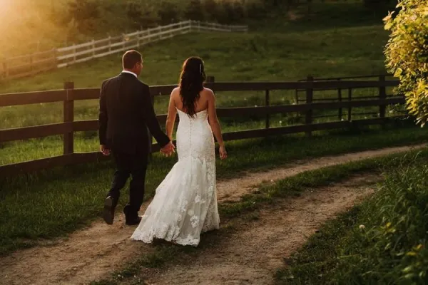 Bride and groom walk by the pastures.