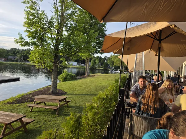 The dining patio next to a swath of grass with picnic tables and the waterfront of Lake Flower