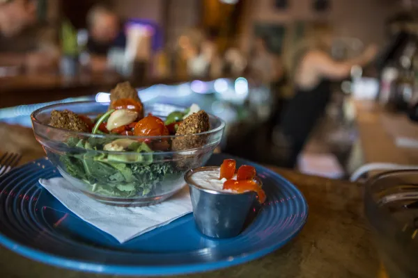 A deep fried food on a blue plate with dipping sauce