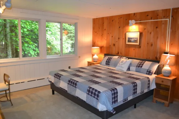 A king sized bed in a wood paneled room with blue quilt