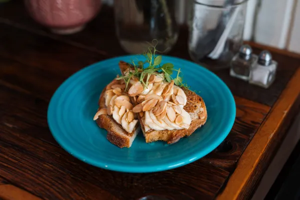 Sliced banana and peanuts on toast on a blue plate.