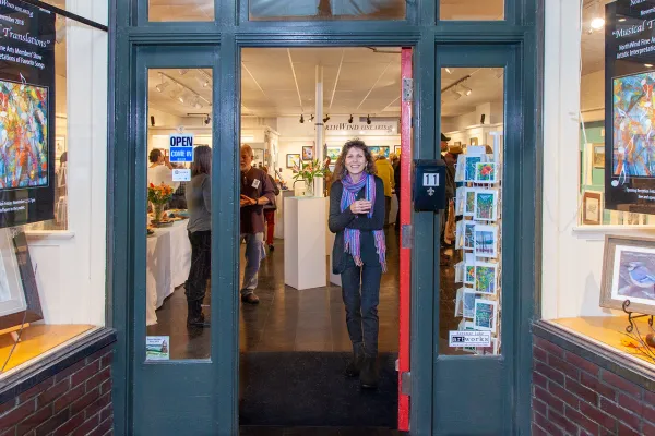 A smiling woman draws you into the gallery from the street.