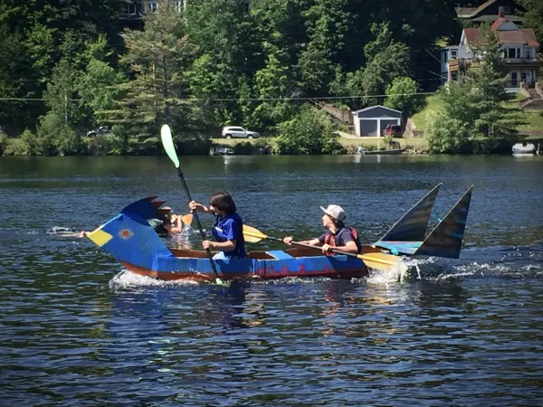 children in a handmade and hand painted cardboard boat on lake flower