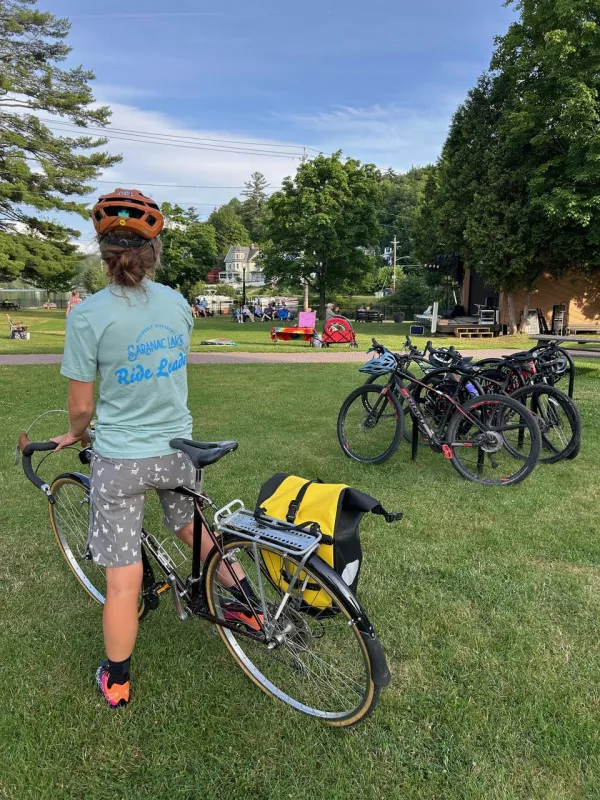 the back of a person on a bicycle at a park with other bikes parked nearby