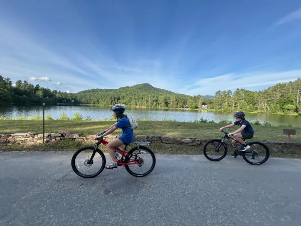 two road cyclists with pond in the background 