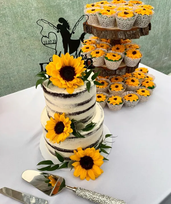 A multi tiered cake, frosted to look like paper birch, with sunflowers and sunflower cupcakes.
