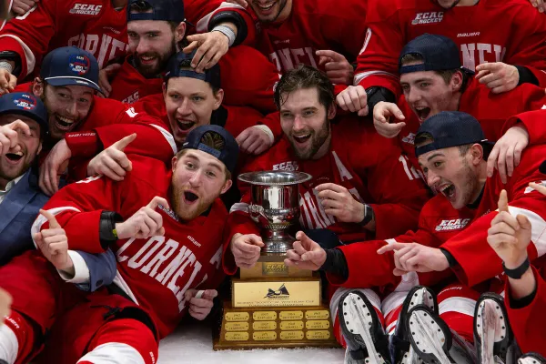 The image captures a close-up of hands reaching out, wearing red hockey gloves. 