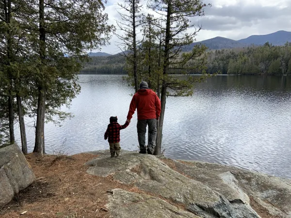 A father and his son walk towards a pond