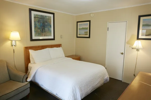 Plush white linens on a queen bed in a yellow walled room at The Ashley.