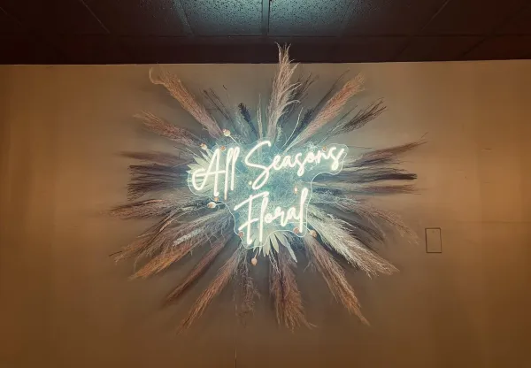 Dried flowers with a neon sign for All Seasons Floral.