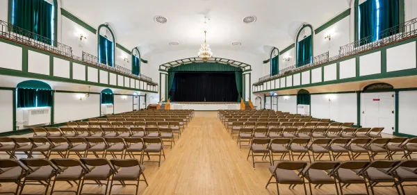 The auditorium with balconies and raised, curtained stage at the Harrietstown Town Hall.