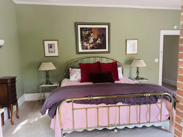 Olive green walls and gold metal bed frame transport you back in time