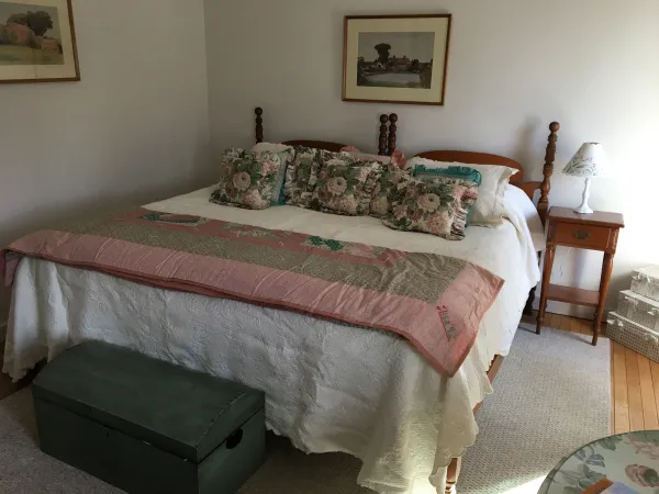 Two twin wooden bed frames, pushed together to make a large bed, covered with quilts and throw pillows.