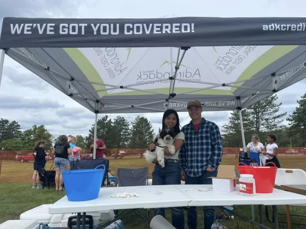 A couple holds a dog in a vendor tent at Bark in the Park