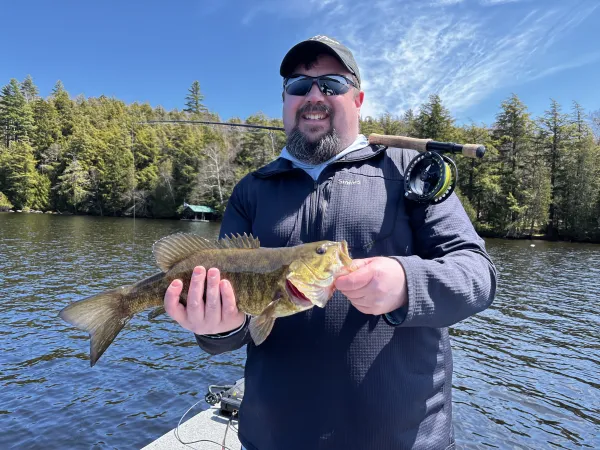 A smiling man holds a fish.