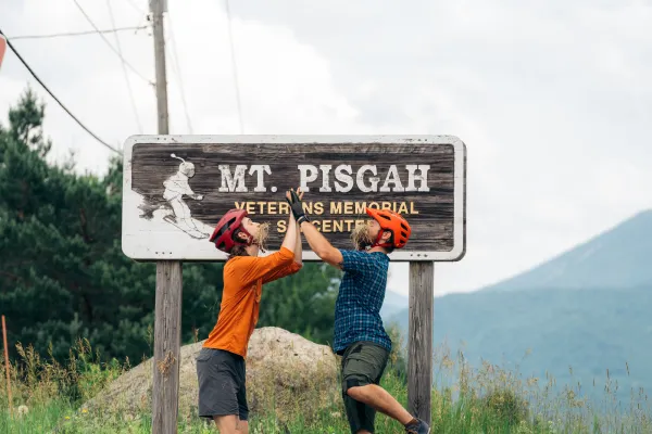 Two mountain bikers being silly in front of the Mt. Pisgah sign