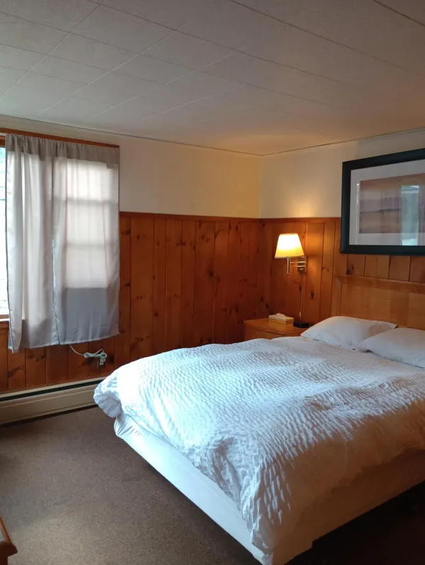Plush white linens on a queen bed in a wood paneled room at The Ashley.