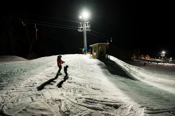 A couple people about to ski down during night skiing at Pisgah
