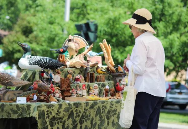 A woman looking at sculptures of birds, gnomes and various objects.