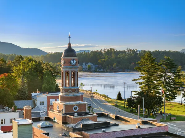 A backed up aerial view of the clock tower at the Harrietstown Town Hall; looking to Lake Flower