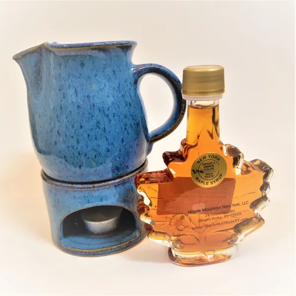 Maple syrup and a cup with a warming stand and candle.