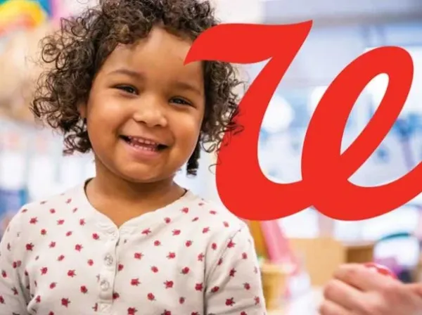 A little girl smiles next to a 'W'