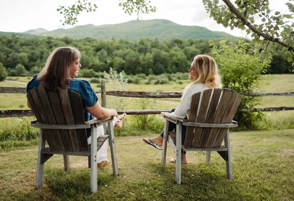 Two women sit in lawn chairs and look at the mountain.