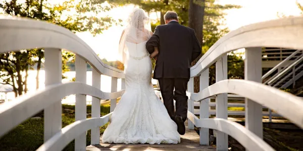 Bride and Groom walk down a white bridge together.