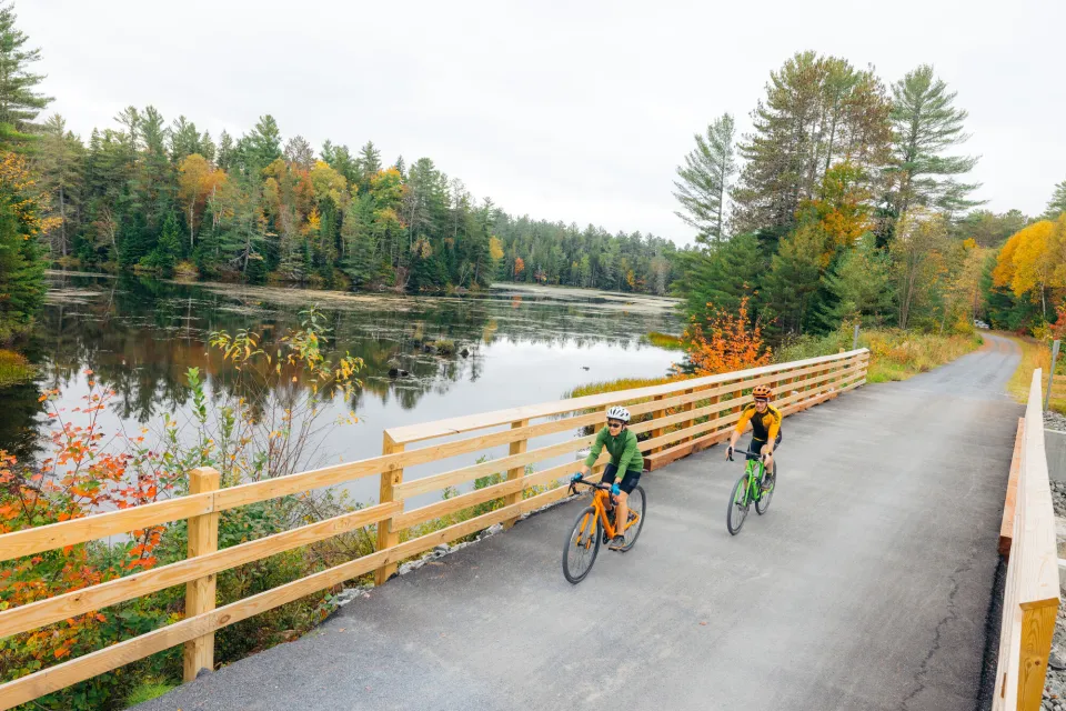 Two people cycle on a paved trail.