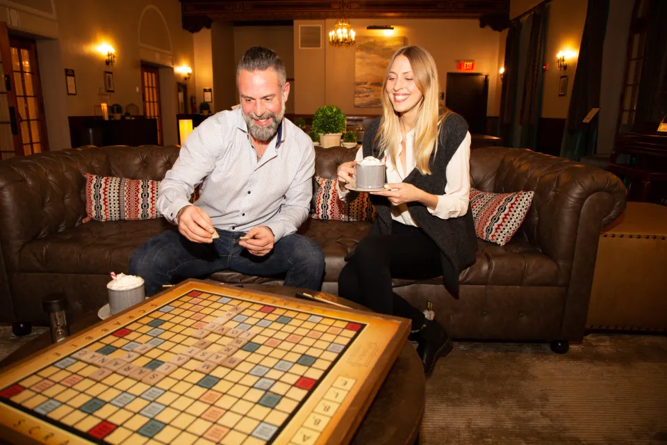 A man and woman play scrabble in a hotel lobby. 