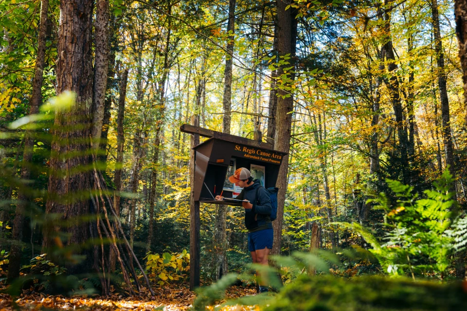 A man signs into a trail in the fall.