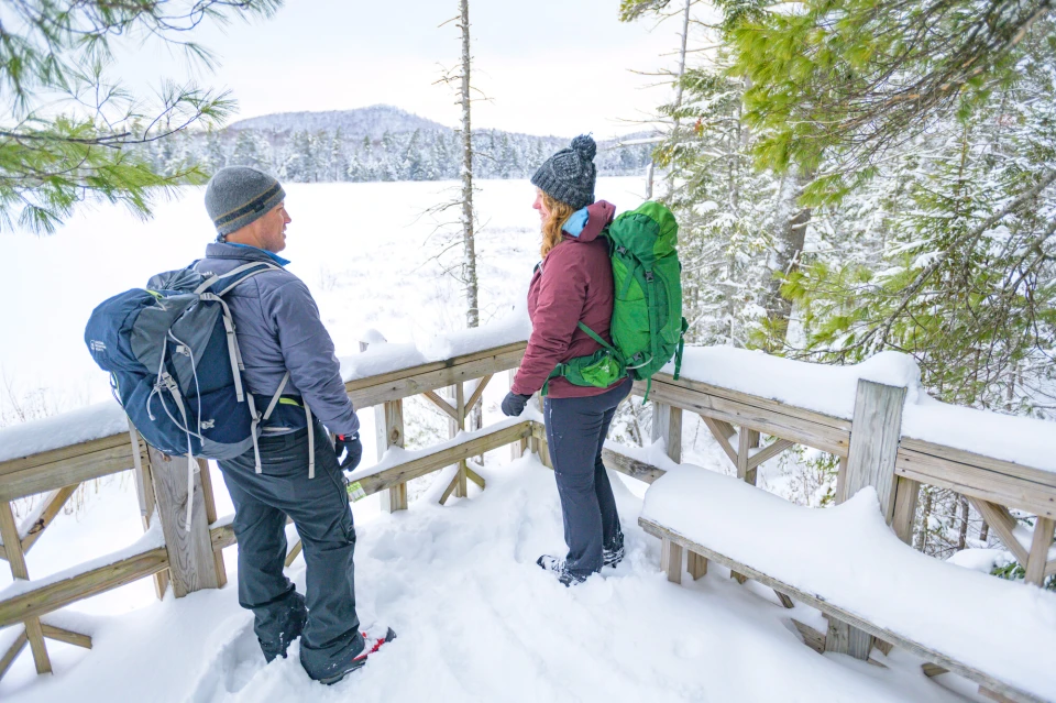 A couple stands on a lookout on a nature trail in winter.