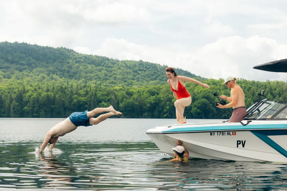 A man and woman jump off a boat.