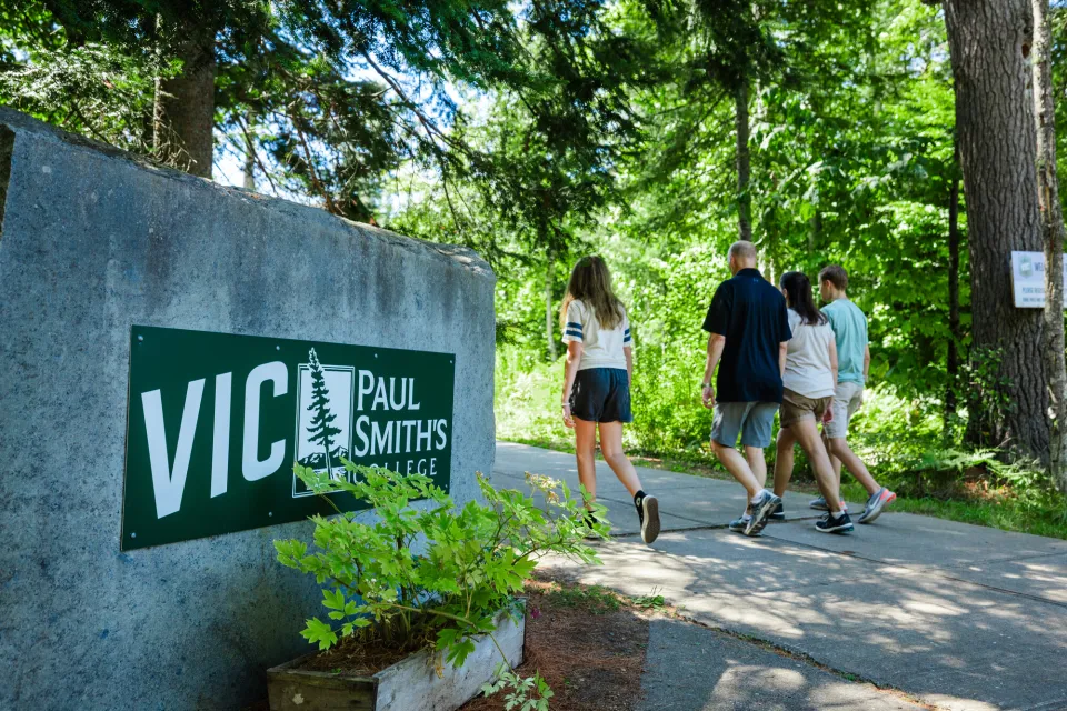 A family walks past the entrance to a wilderness preserve. 