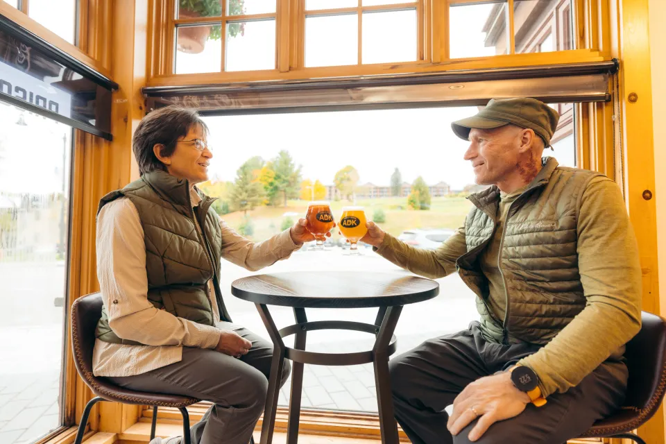 A man and woman cheers beers at a brewery.