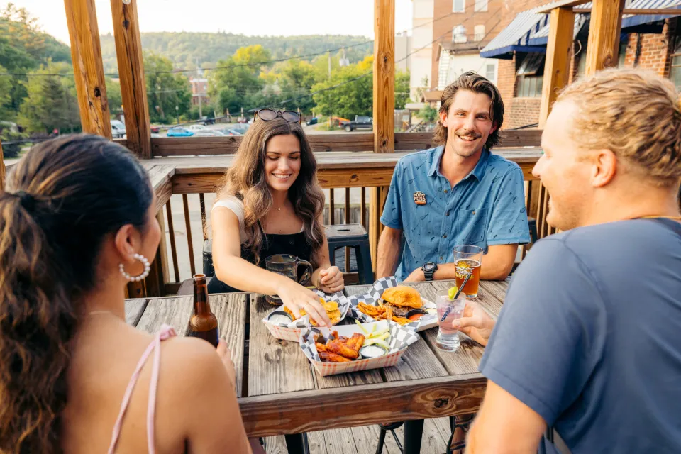 A group of friends enjoy dinner at a restaurant outside.